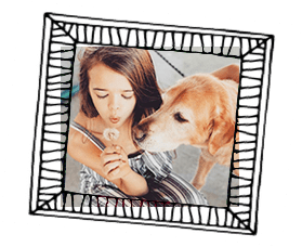 A little girl and her dog hanging out together at home and playing with a dandelion.