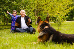 Dog reading body language of elderly man and his granddaughter.